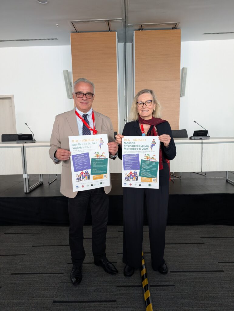 An image of two people standing and holding a poster