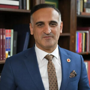 Photo of Taner Beyoğlu in front of bookshelves © National Library of Türkiye